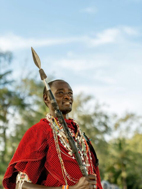 Maasai warrior in traditional attire holding a spear, outdoors in Mombasa, Kenya.